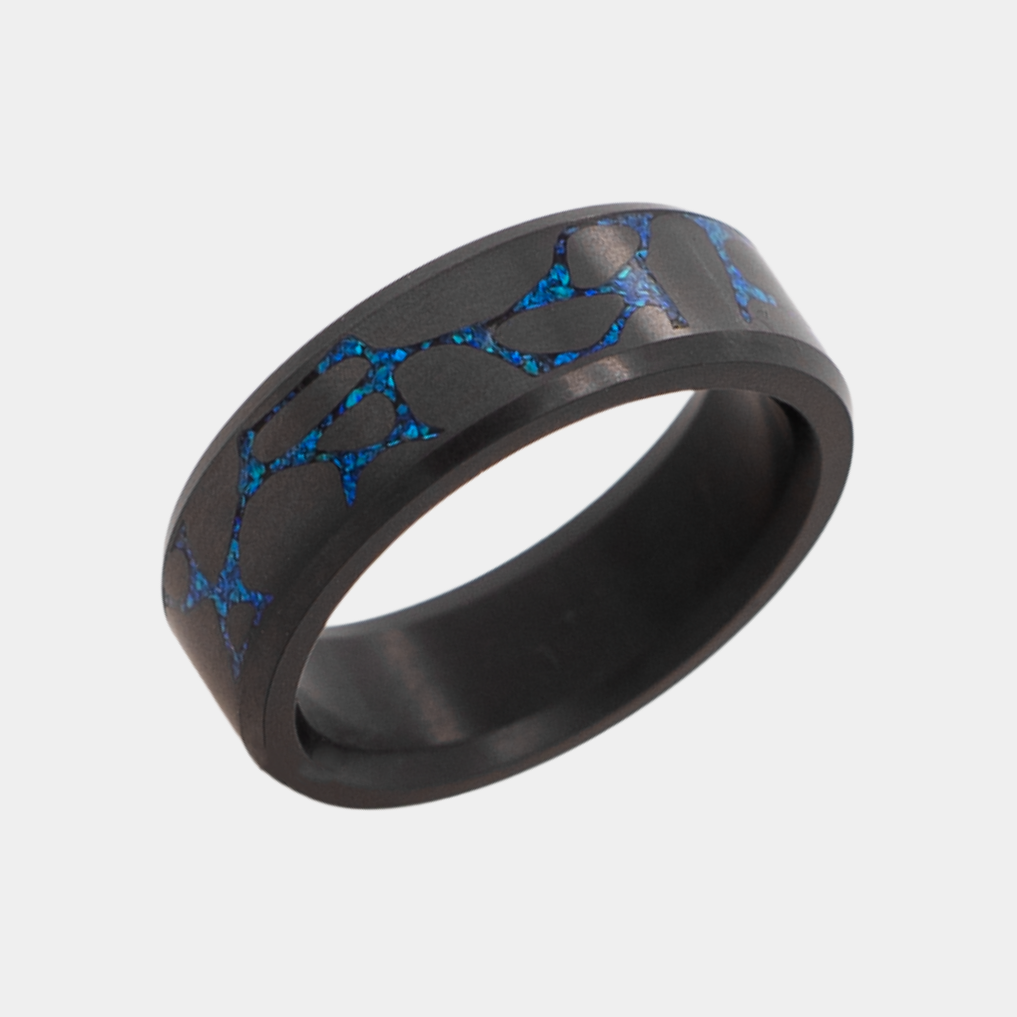 Solid Black Diamond ring with laser engraved river stone inlay filled with blue opal on a light gray background