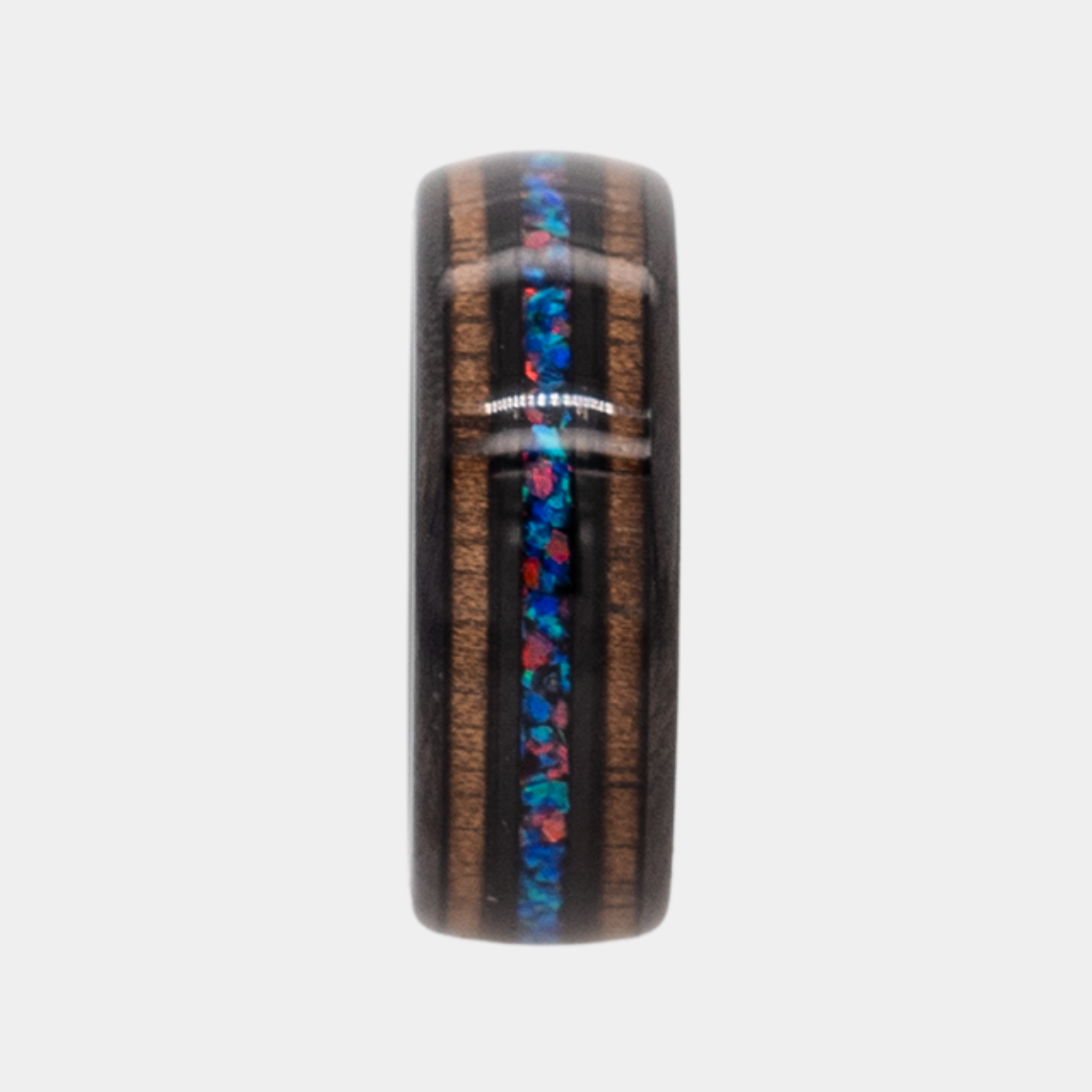Nereus ring – Black Tungsten featuring Double Koa Wood and Crushed Opal Inlays from the Hustler Collection. Ring standing upright to show profile and thickness.