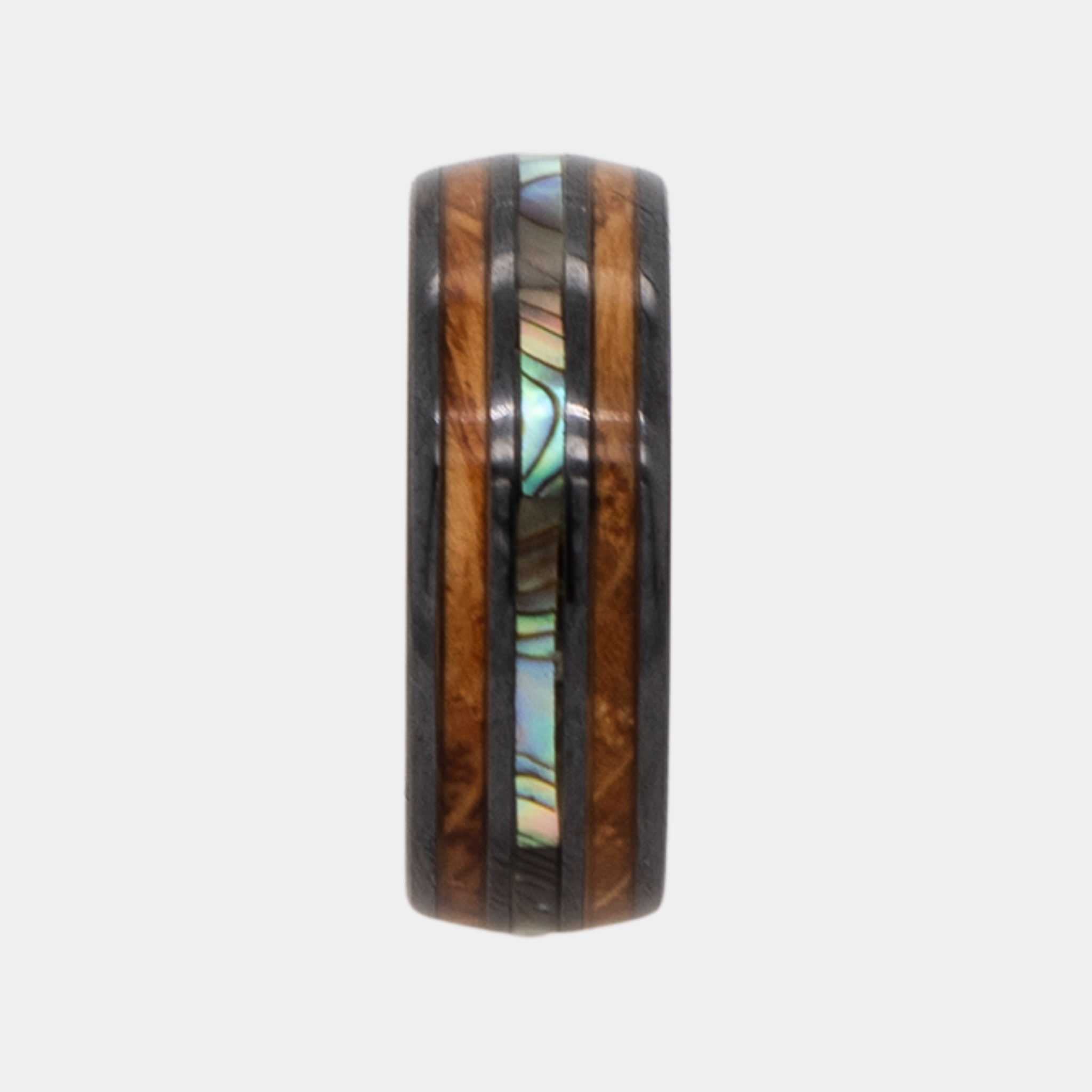 Odysseus ring – Polished Black Ceramic, Featuring a Double Whiskey Barrel Wood Inlay and Abalone Shell Inlay from the Hustler Collection. Ring standing upright to show profile and thickness.