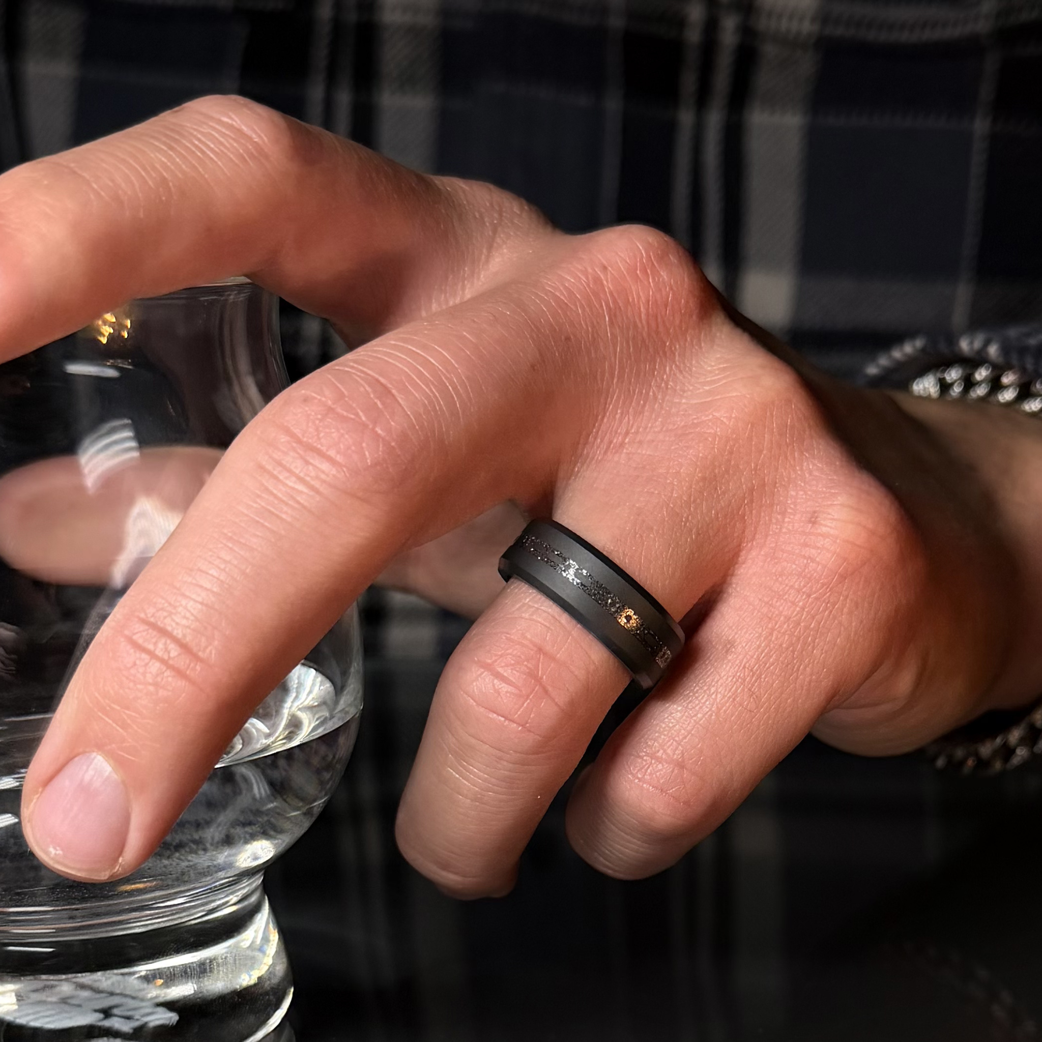 Hand wearing Solid Black Diamond ring with a laser engraved inlay reading "I love you" in morse code, filled with meteorite on a reflective background