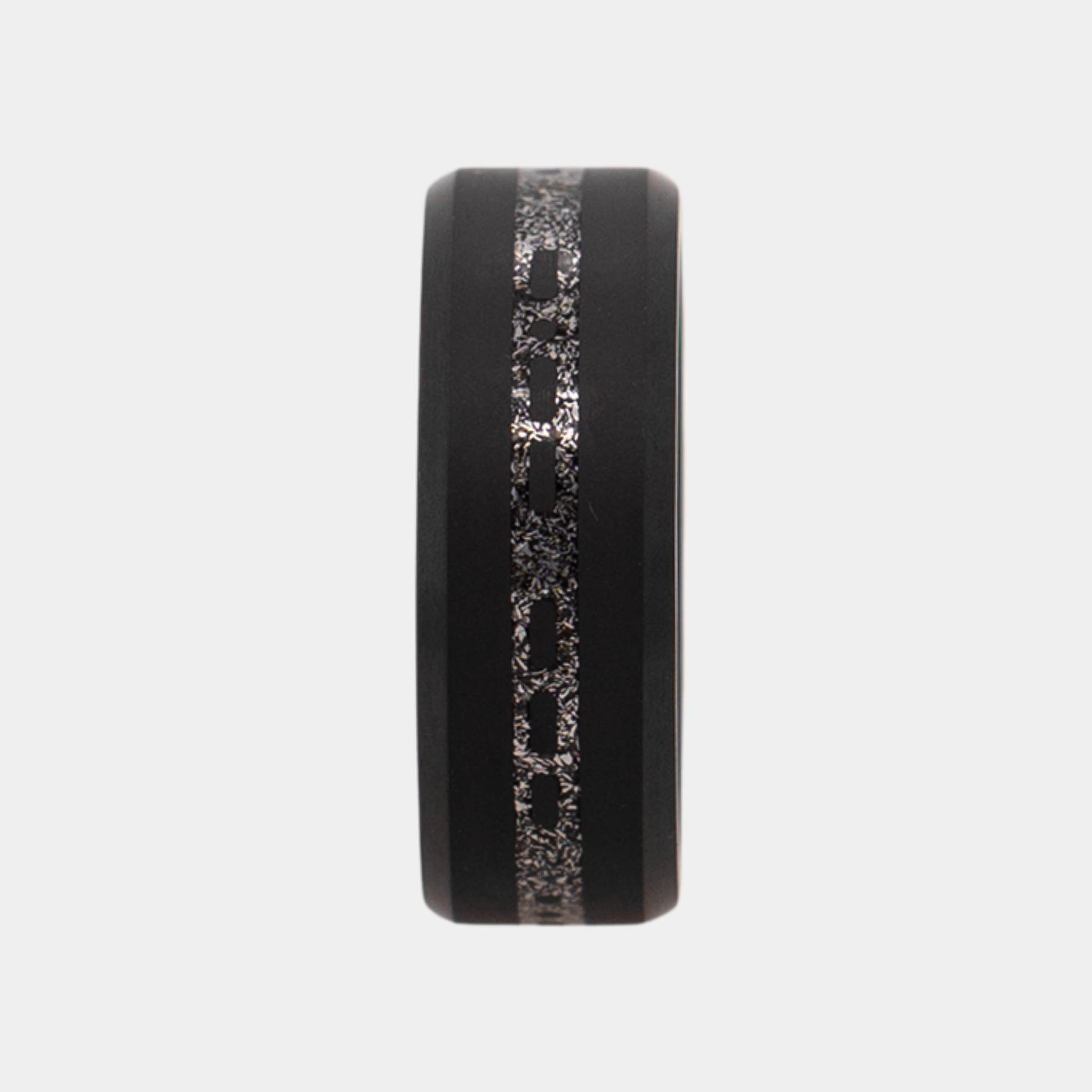 Vertical view of Solid Black Diamond ring with a laser engraved inlay reading "I love you" in morse code, filled with meteorite on a grey background.