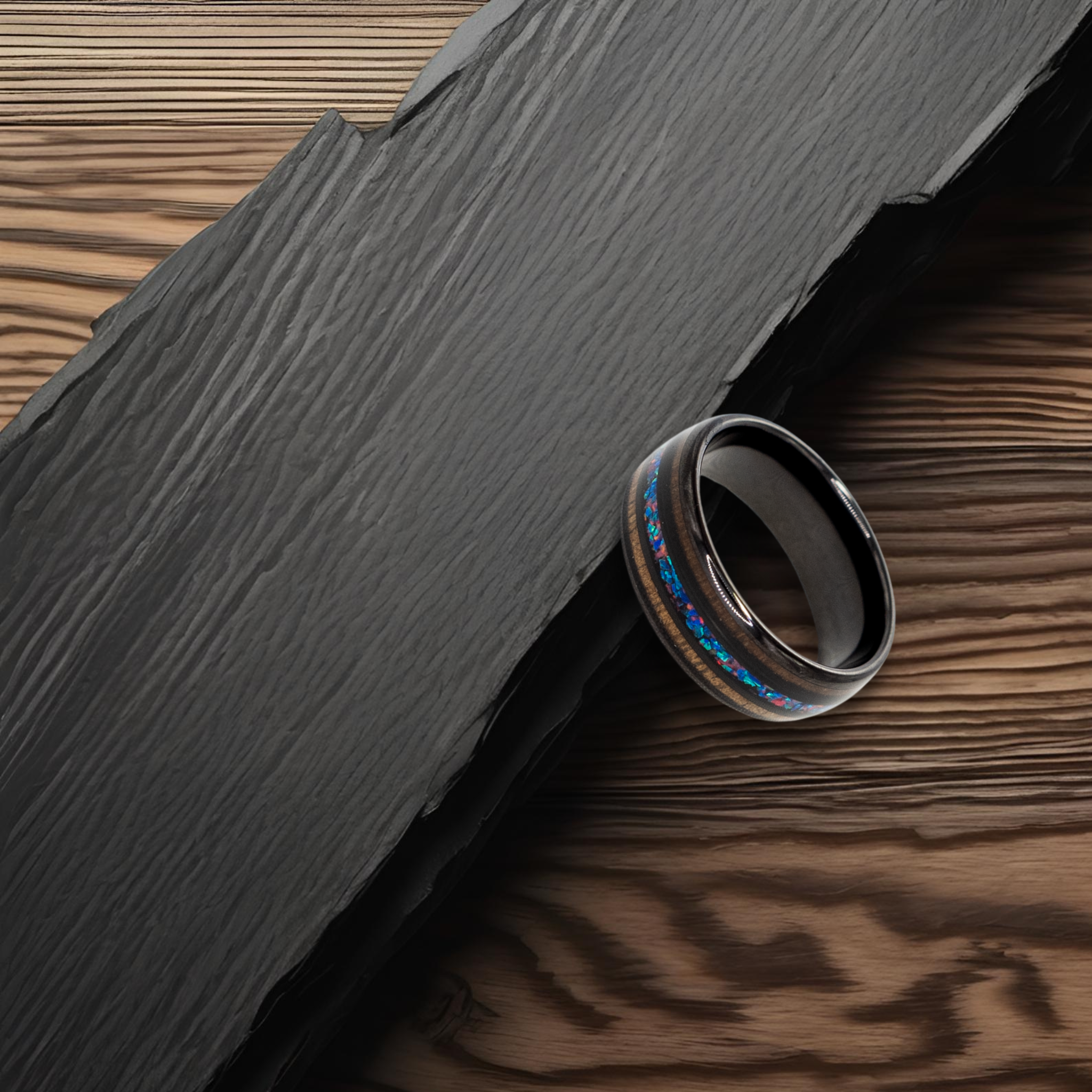 Nereus ring – solid black diamond with polished beveled edges from the Hustler Collection. Lifestyle shot, placed on textured rock.