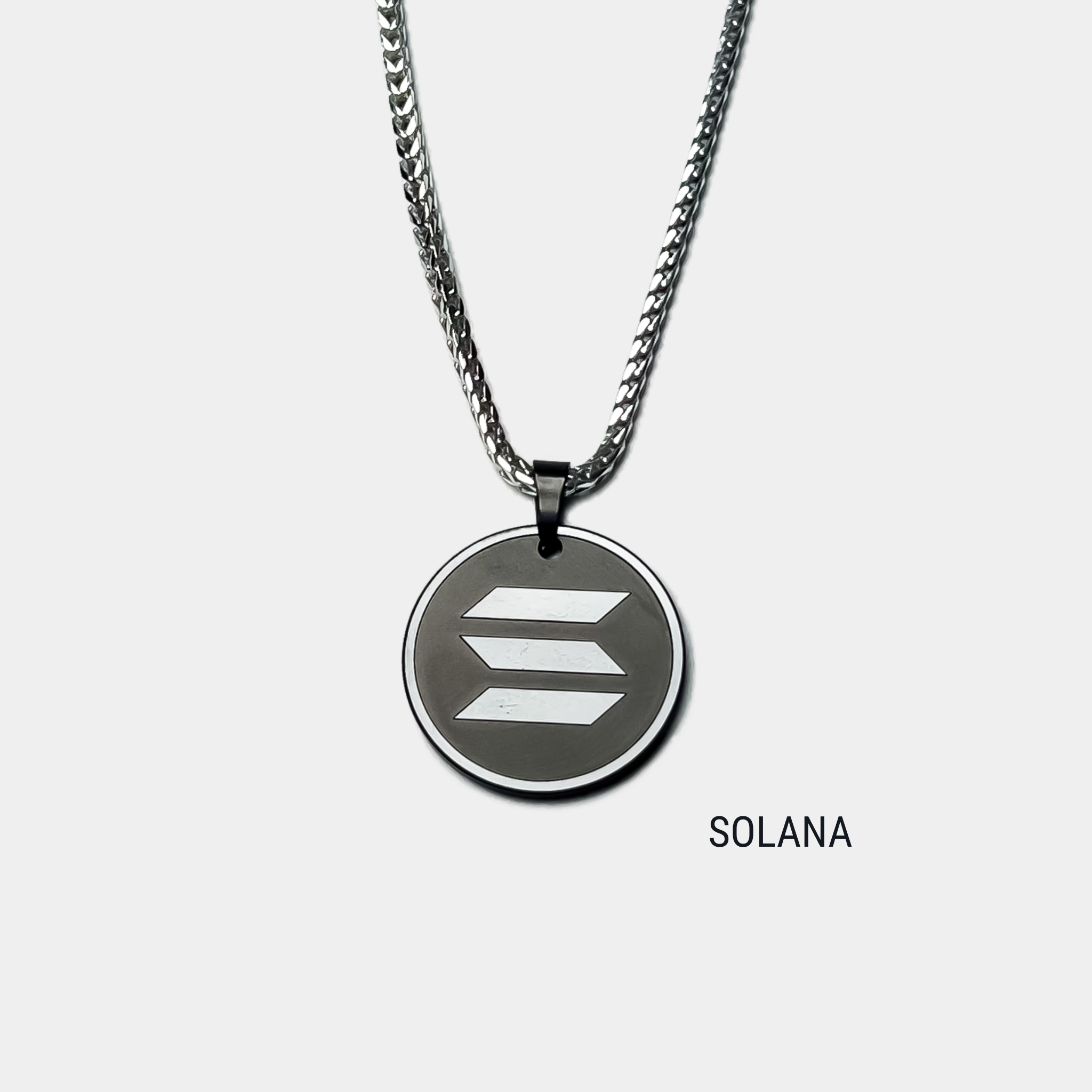 Photo of round solid black diamond pendant with solana symbol engraved, attached to silver chain